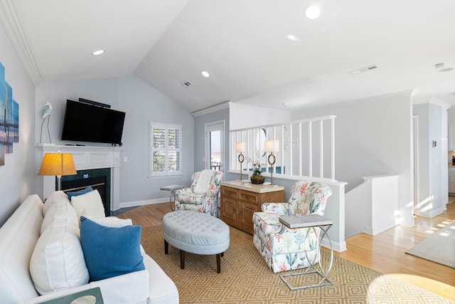 living area with lofted ceiling, light wood finished floors, a fireplace with flush hearth, and visible vents