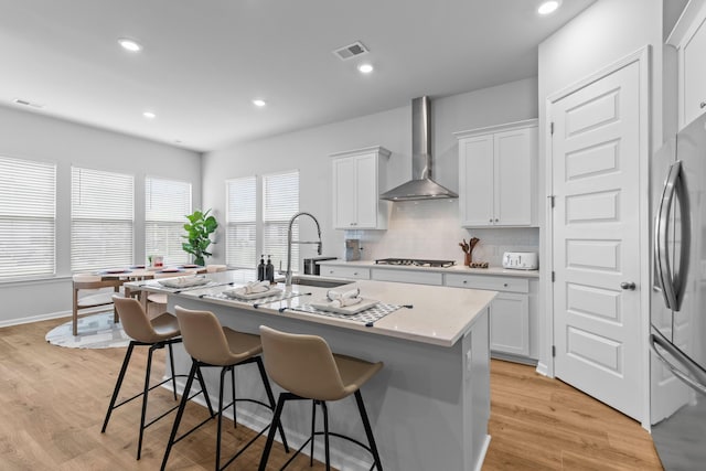 1107 Bellwether Ln, Summerville, SC 29485 - kitchen featuring appliances with stainless steel finishes, wall chimney range hood, a breakfast bar, an island with sink, and backsplash