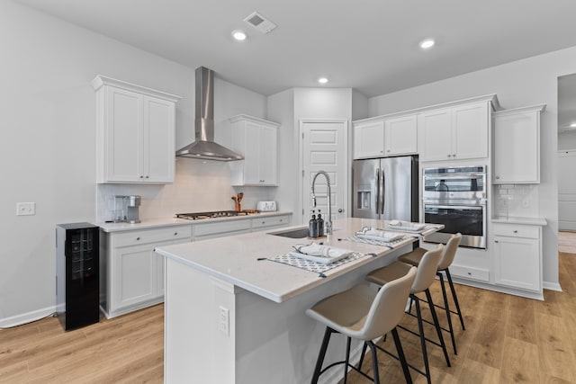 1107 Bellwether Ln, Summerville, SC 29485 - kitchen featuring appliances with stainless steel finishes, wall chimney range hood, wine cooler, light wood-style floors, and recessed lighting