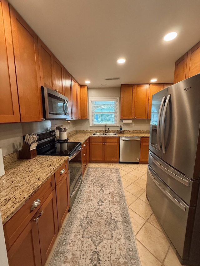 kitchen featuring light stone counters, light tile patterned floors, sink, and appliances with stainless steel finishes