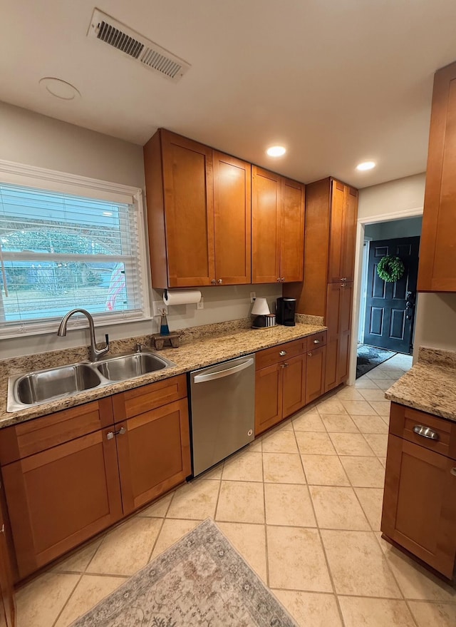 kitchen with dishwasher, light tile patterned floors, light stone counters, and sink