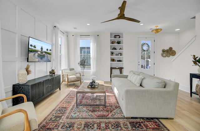 living room with light wood-type flooring, ceiling fan, and a healthy amount of sunlight