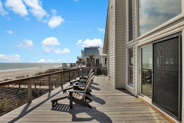 wooden terrace featuring a water view and a view of the beach