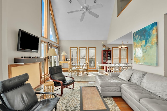 living area featuring a healthy amount of sunlight, ceiling fan, a towering ceiling, and wood finished floors