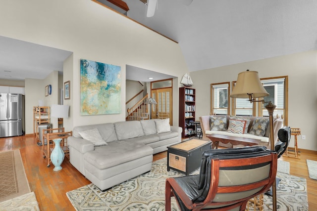 living room with high vaulted ceiling, stairway, and wood finished floors