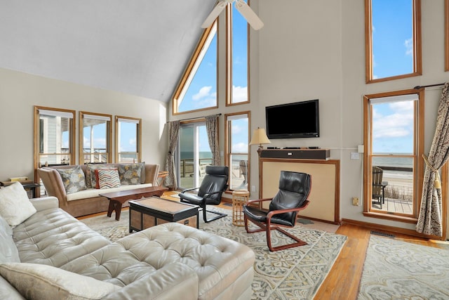 living area featuring high vaulted ceiling, a healthy amount of sunlight, visible vents, and wood finished floors