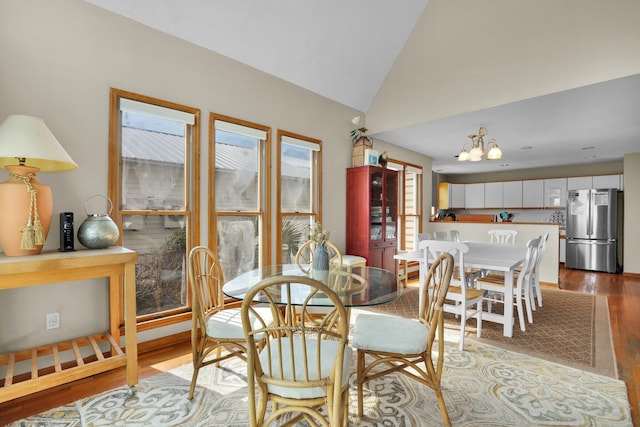 dining space with vaulted ceiling, wood finished floors, and a notable chandelier