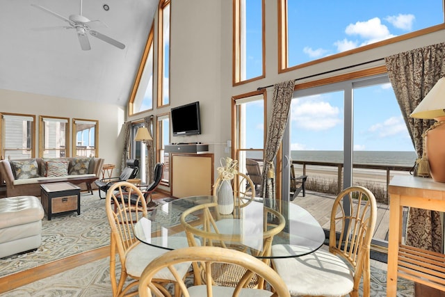 dining area with high vaulted ceiling, wood finished floors, a ceiling fan, and a healthy amount of sunlight