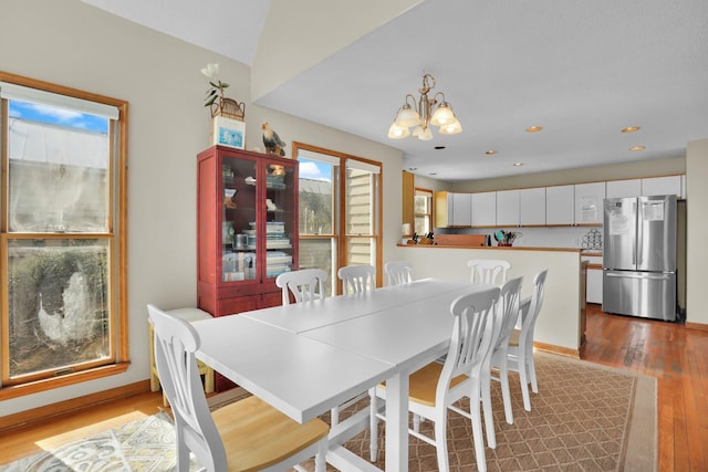 dining room featuring baseboards, recessed lighting, hardwood / wood-style flooring, and an inviting chandelier