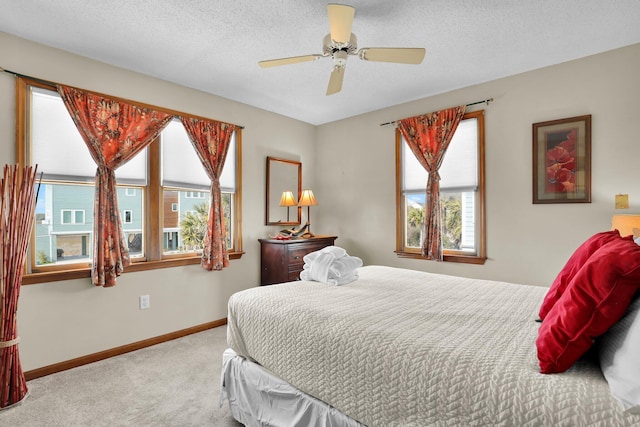 bedroom with a textured ceiling, carpet floors, ceiling fan, and baseboards