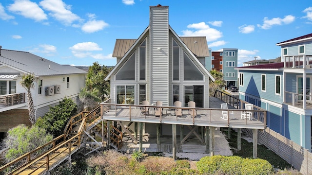 rear view of house with a chimney, metal roof, a standing seam roof, stairs, and a deck