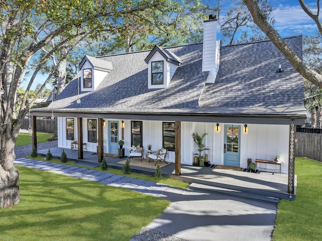 rear view of house featuring a lawn and covered porch