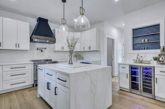 kitchen featuring white cabinetry, wall chimney range hood, and high end stainless steel range oven