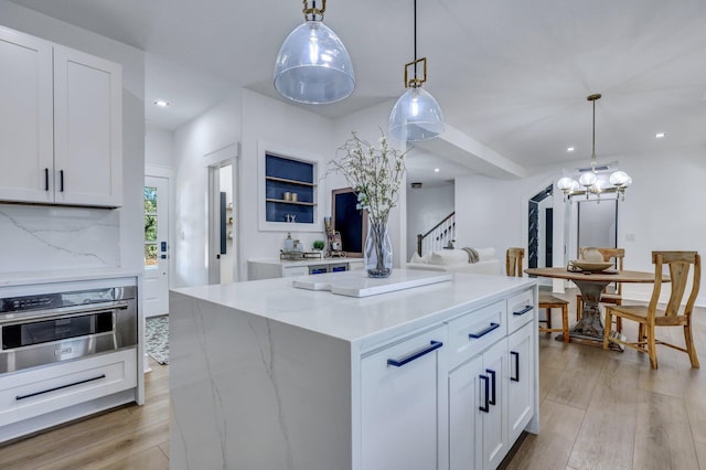 kitchen featuring stainless steel oven, white cabinets, and decorative light fixtures