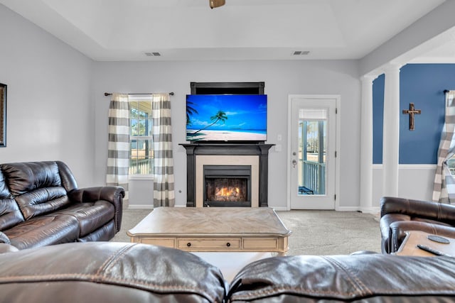 carpeted living room with a raised ceiling and ornate columns