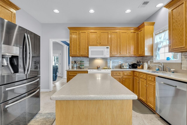 kitchen featuring decorative backsplash, sink, stainless steel appliances, and a kitchen island