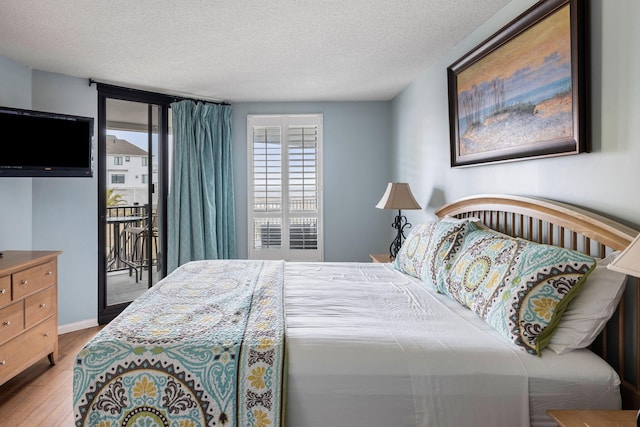 bedroom featuring hardwood / wood-style floors, access to exterior, and a textured ceiling