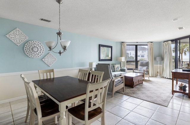 tiled dining space with a notable chandelier and a textured ceiling