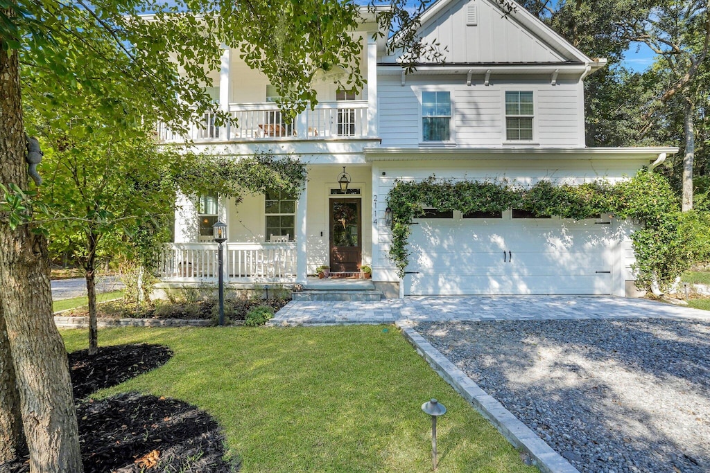 view of front of home featuring covered porch, a balcony, a front lawn, and a garage