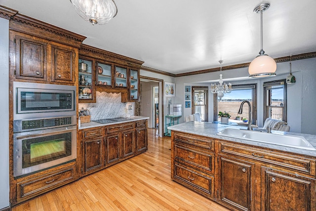 kitchen with sink, appliances with stainless steel finishes, backsplash, light hardwood / wood-style floors, and decorative light fixtures