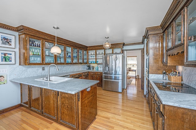 kitchen with sink, hanging light fixtures, light wood-type flooring, appliances with stainless steel finishes, and kitchen peninsula