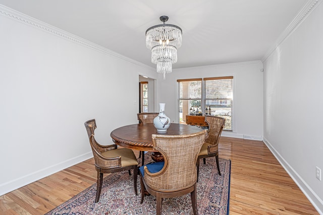 dining room with crown molding, a notable chandelier, and light wood-type flooring