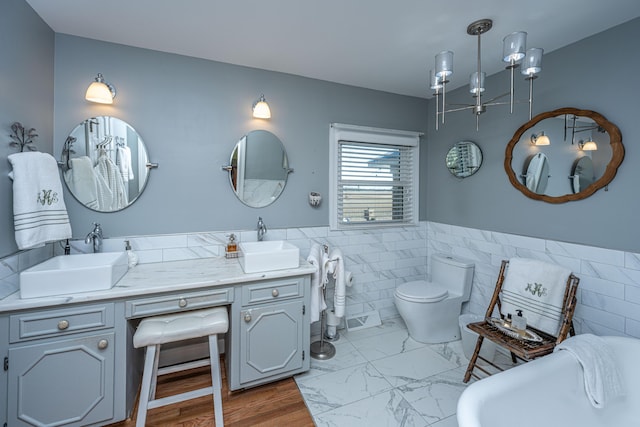 bathroom featuring vanity, toilet, a bathtub, and tile walls