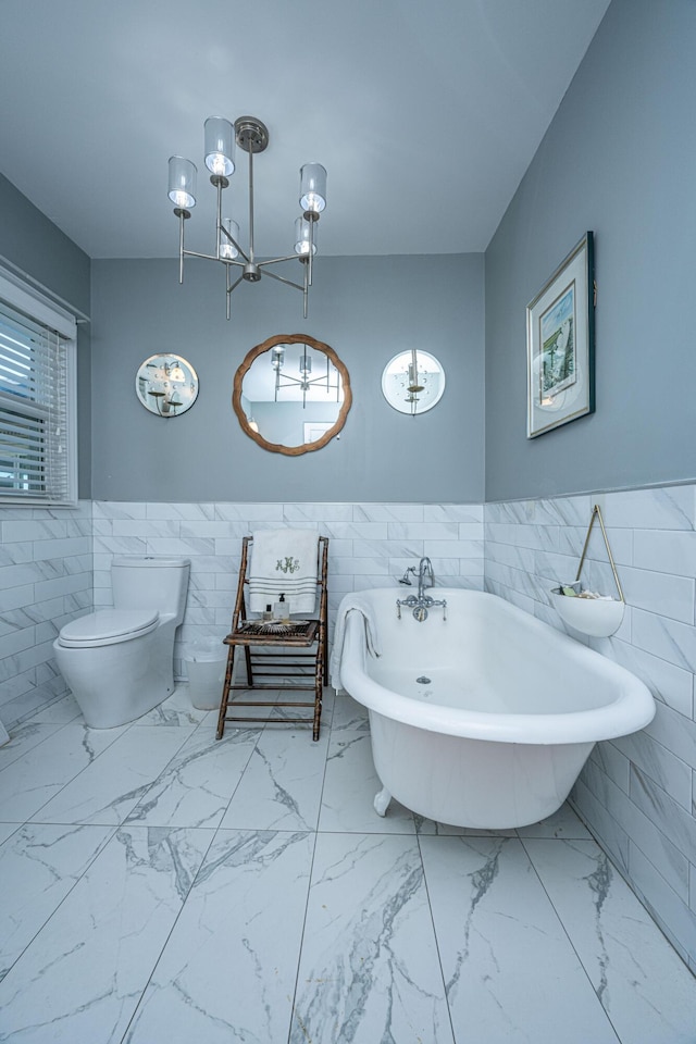 bathroom featuring tile walls, a tub to relax in, and toilet