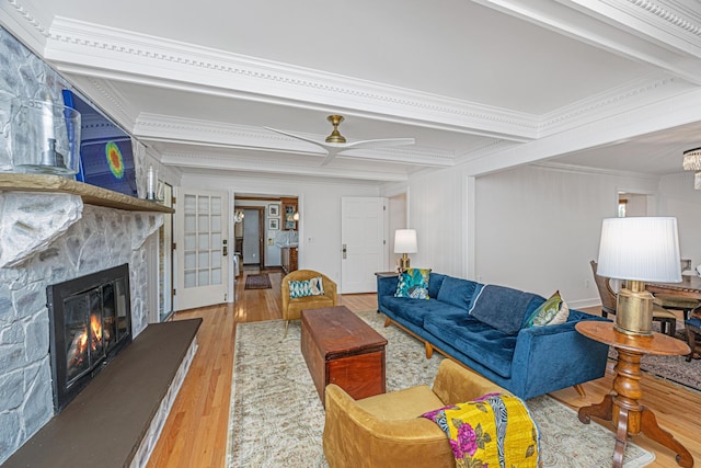 living room featuring french doors, beam ceiling, crown molding, light hardwood / wood-style flooring, and a fireplace