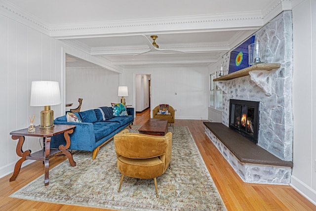 living room with wood-type flooring, ornamental molding, and a fireplace