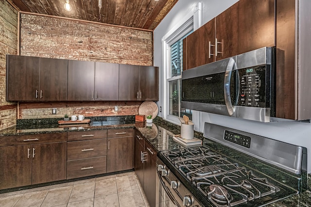173 Fishburne St, Charleston, SC 29403 - kitchen with appliances with stainless steel finishes, wooden ceiling, dark stone counters, dark brown cabinetry, and light tile patterned floors