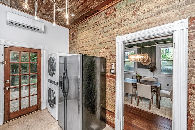 173 Fishburne St, Charleston, SC 29403 - laundry area with a wall mounted AC, wooden walls, stacked washer and clothes dryer, and a chandelier