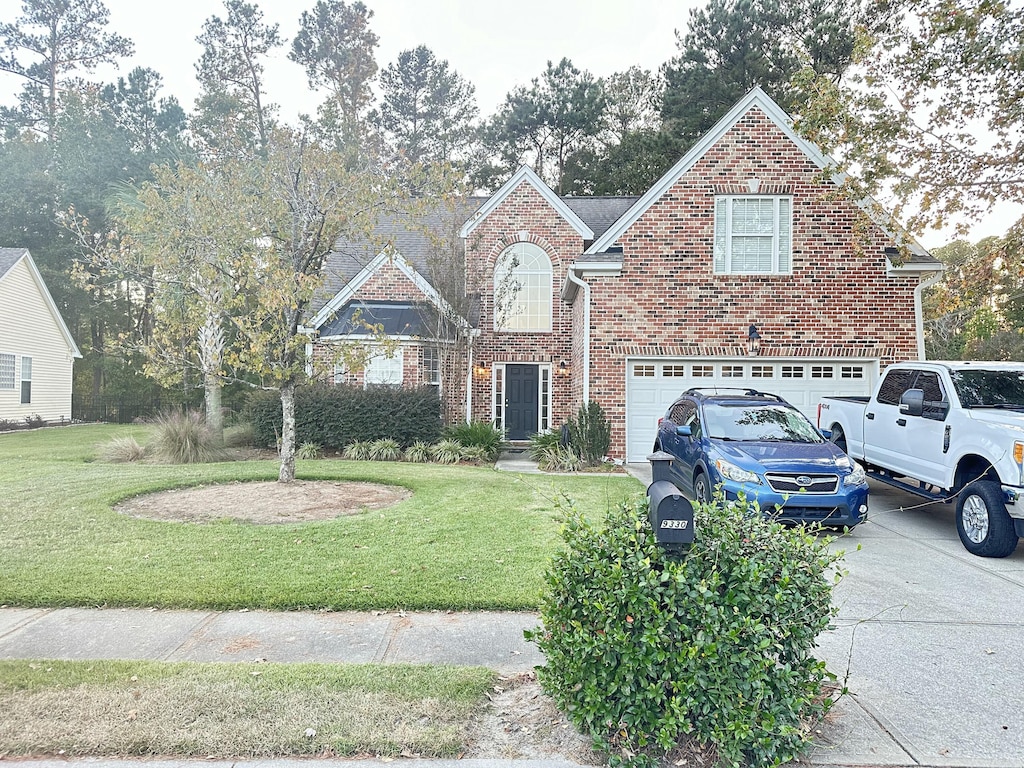 traditional-style home featuring brick siding, driveway, an attached garage, and a front yard