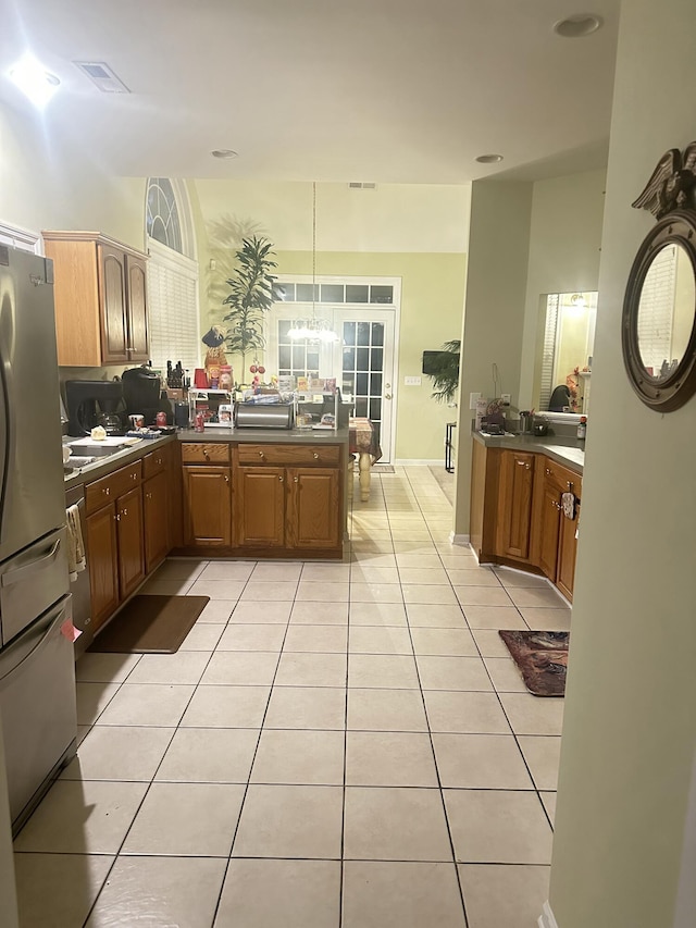 kitchen with light tile patterned floors, dark countertops, a peninsula, and freestanding refrigerator