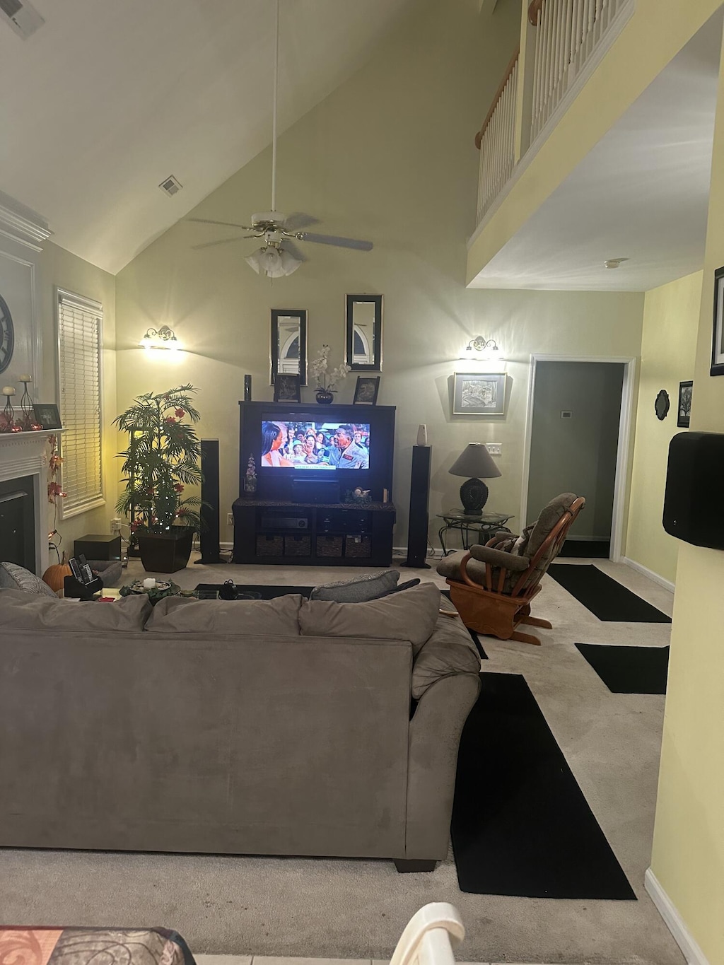 living area with a fireplace, visible vents, carpet floors, and high vaulted ceiling