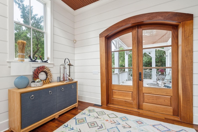 foyer entrance with french doors, wooden walls, dark hardwood / wood-style floors, and crown molding