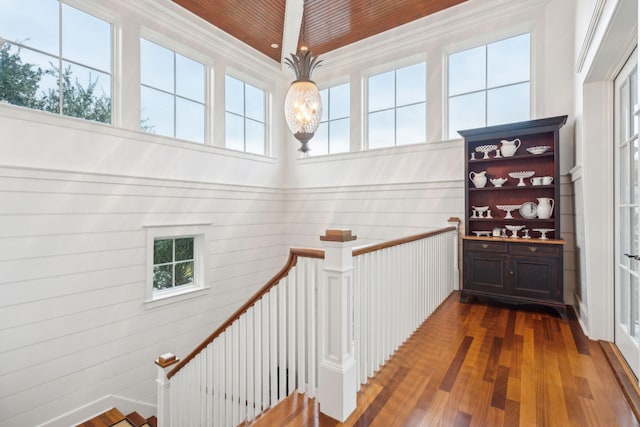 stairway with hardwood / wood-style flooring, wood walls, and a high ceiling