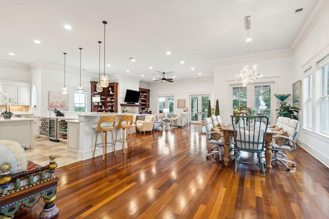 dining space featuring wood-type flooring, ceiling fan with notable chandelier, ornamental molding, and a wealth of natural light