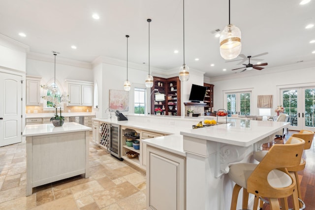 kitchen with hanging light fixtures, beverage cooler, a spacious island, and french doors