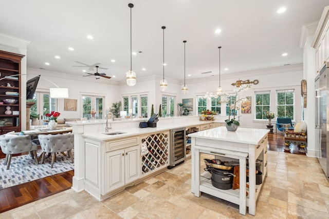 kitchen featuring hanging light fixtures, light hardwood / wood-style floors, a large island with sink, wine cooler, and ceiling fan