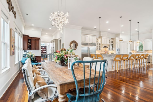 dining area with ornamental molding, dark hardwood / wood-style floors, an inviting chandelier, and sink