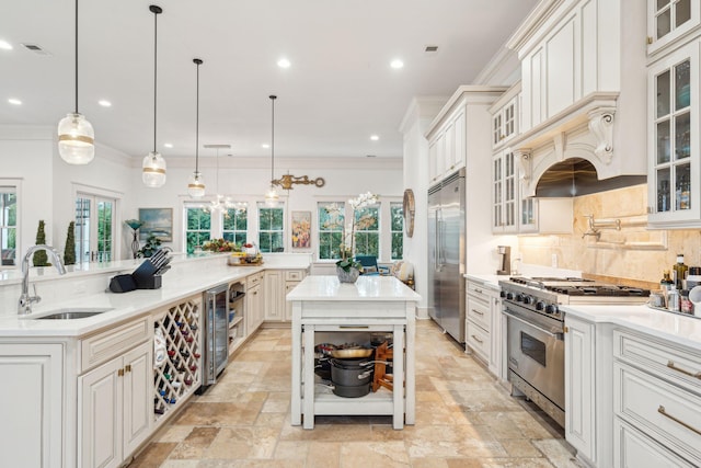 kitchen with pendant lighting, high end appliances, a center island with sink, and sink