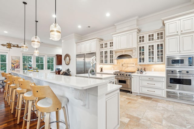 kitchen featuring decorative backsplash, built in appliances, a large island, and decorative light fixtures