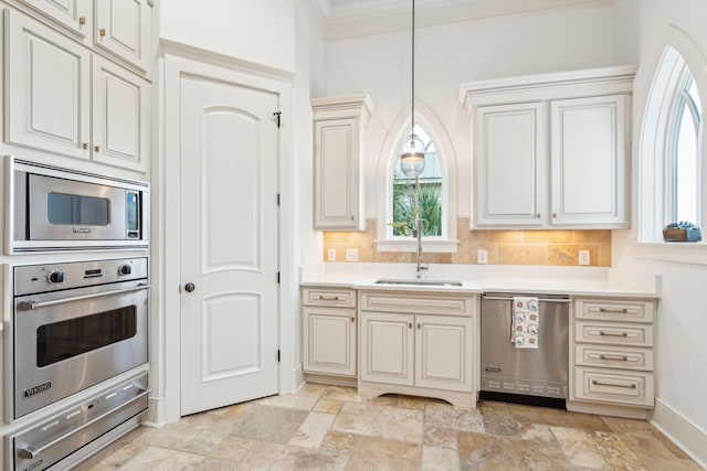 kitchen with appliances with stainless steel finishes, tasteful backsplash, decorative light fixtures, and sink