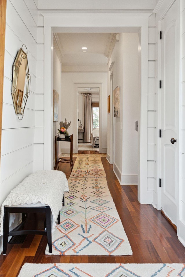 corridor featuring wood walls, crown molding, and dark wood-type flooring