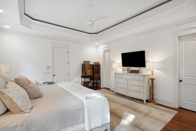 bedroom featuring ceiling fan, hardwood / wood-style flooring, a tray ceiling, and crown molding