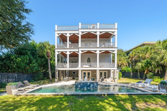 back of property with a balcony, a fenced in pool, a lawn, ceiling fan, and a patio area