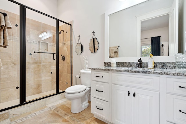 bathroom featuring a shower with door, vanity, and toilet