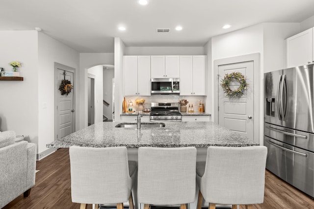 404 Omaha Dr, Moncks Corner, SC 29461 - kitchen with appliances with stainless steel finishes, arched walkways, light stone countertops, decorative backsplash, and white cabinetry