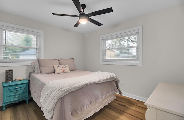 bedroom featuring baseboards, multiple windows, dark wood-style floors, and a ceiling fan